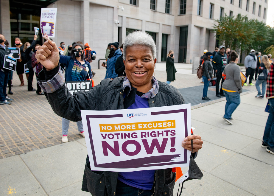 Dr. Turner holding a "Voting Rights Now" sign with her fist raised