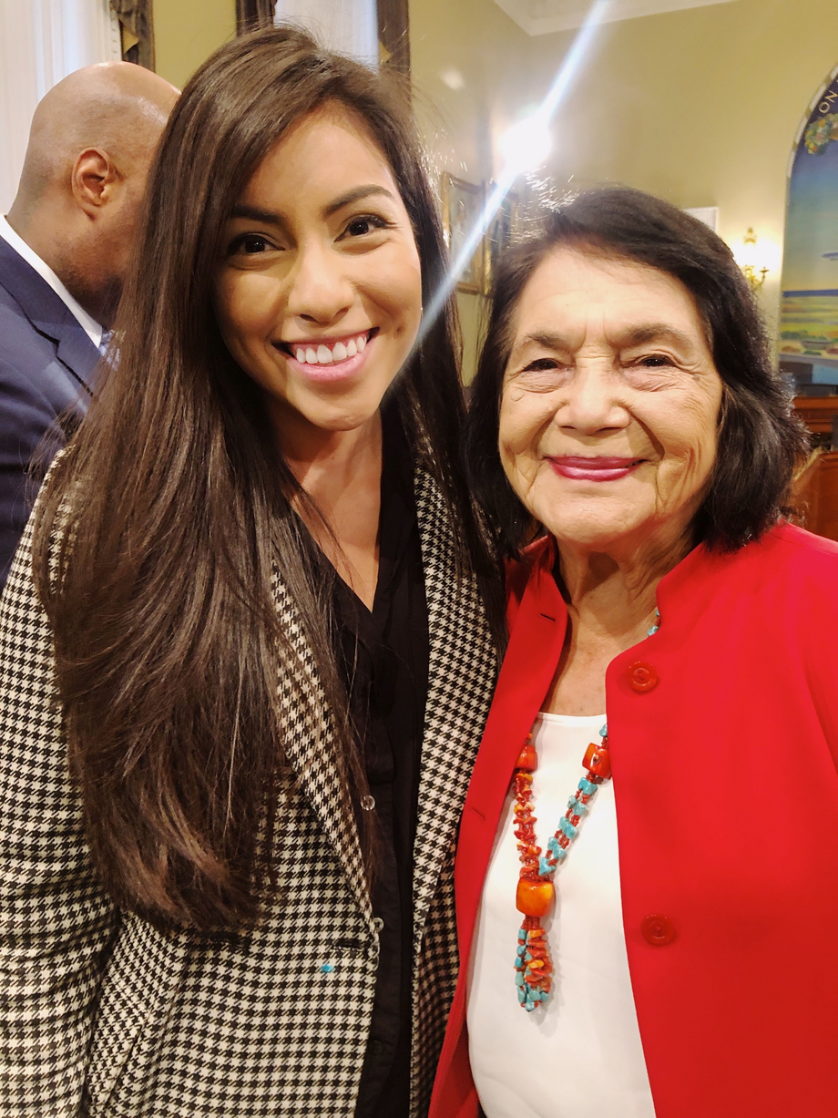 A LWV member standing and smiling with activist Dolores Huerta