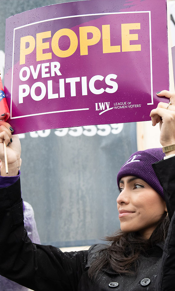 A member of LWV holding a sign that says "People Over Politics"