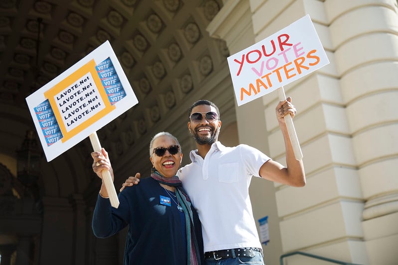 Man and woman holding picket signs that say 