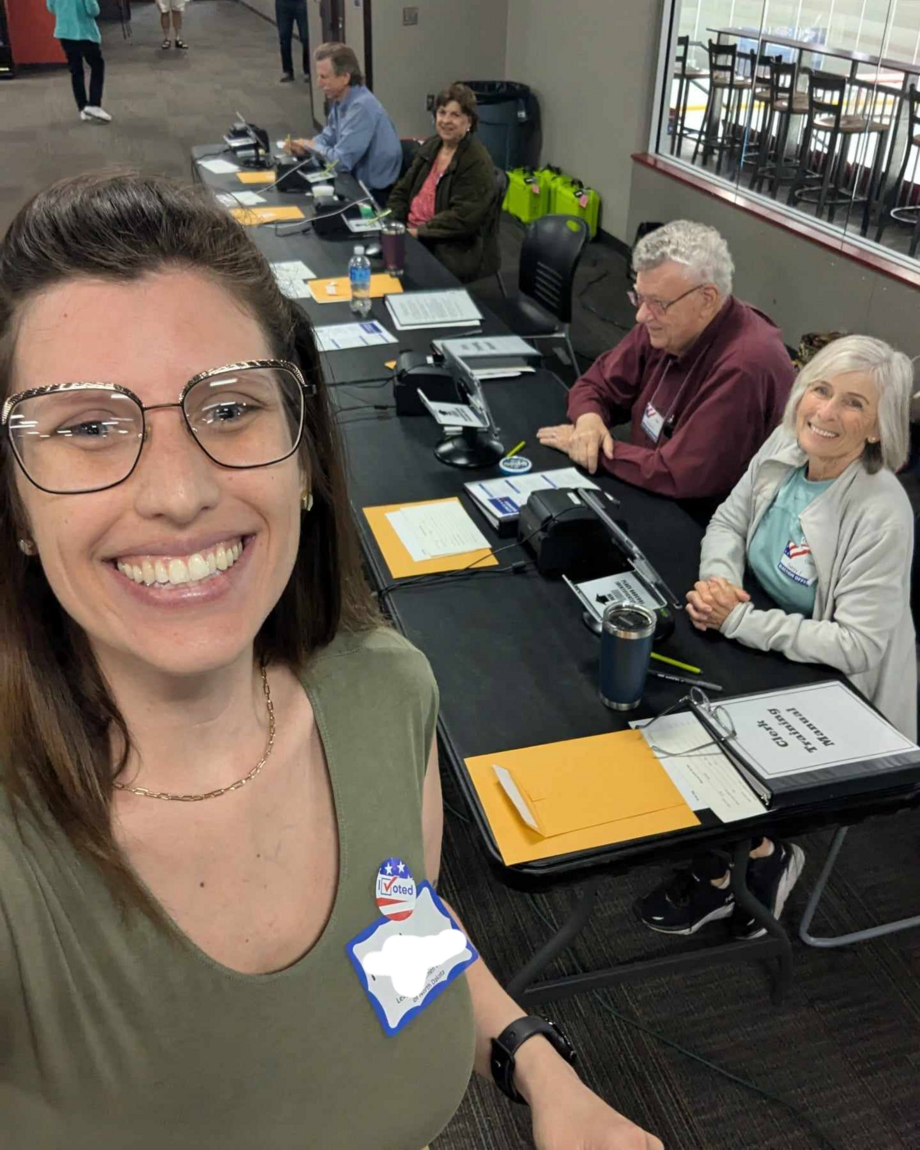 An election worker from North Dakota takes a selfie with other election workers seated in the background