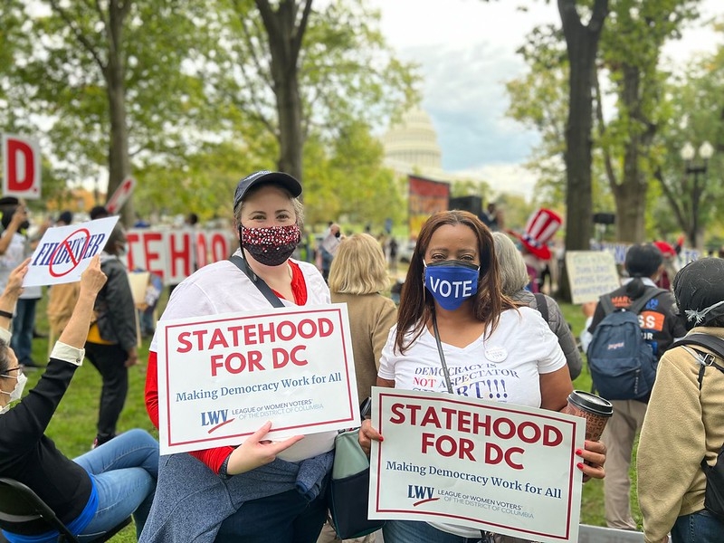 Two people in masks holding signs that say 
