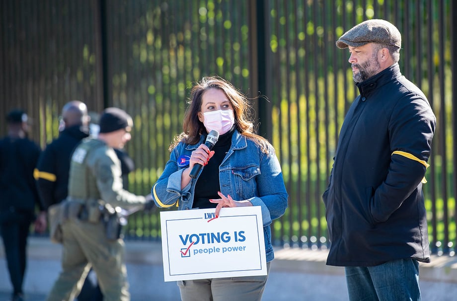 Virginia Kase Solomón at a No More Excuses rally holding a Voting is People Power sign