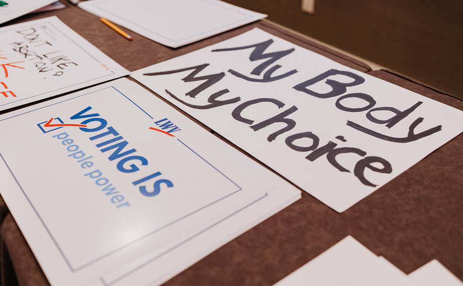 Two protest signs, one saying "Voting is people power" and the other saying "my body my choice."