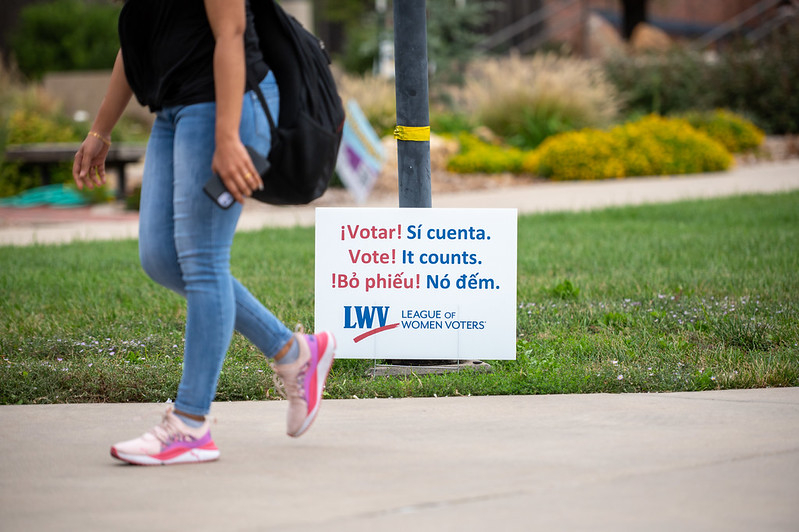Person walking past a voting sign that says 