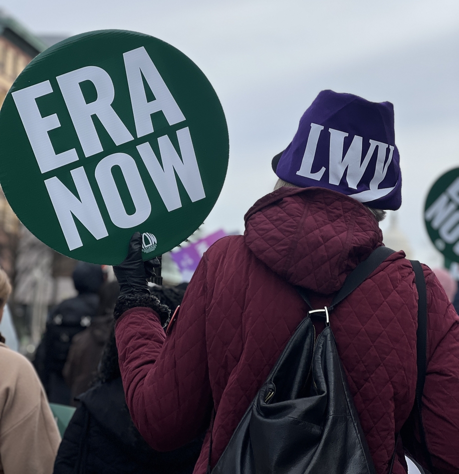 A person in an LWV hat holding a sign that says