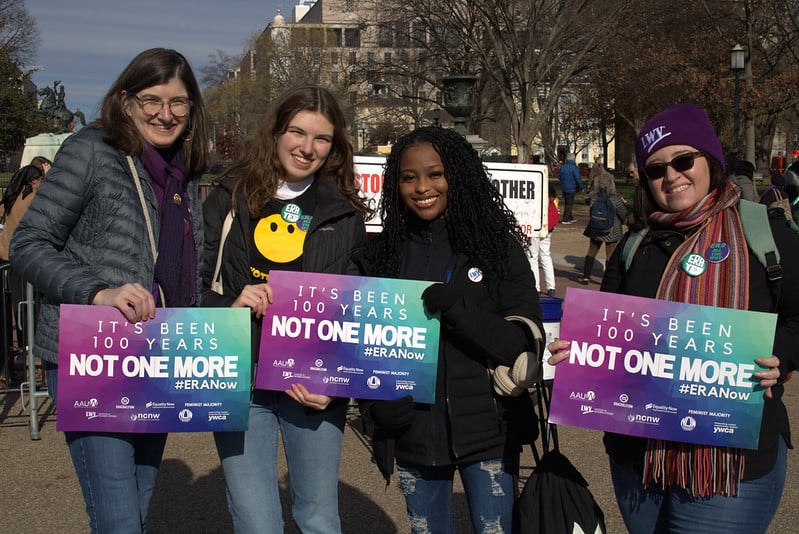 Four League members at an ERA rally holding rally signs and smiling