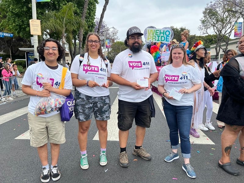 VOTE411 volunteers on the Pride Parade route holding VOTE411 buttons and palm cards