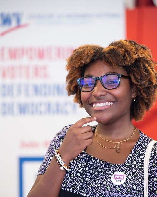 A girl smiling at the camera wearing a VOTE411 button