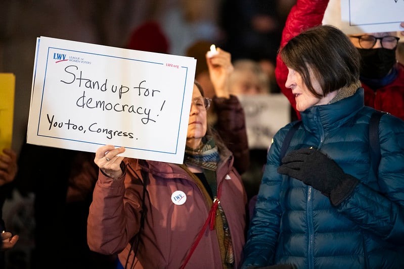 Two women, one holding a sign that says