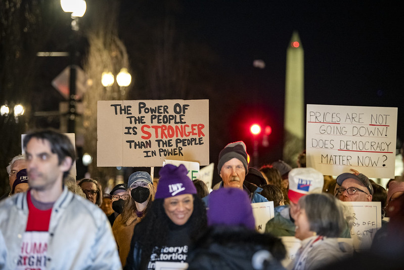 A crowd of protestors at night with the Washington Monument in the background