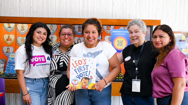 Five woman holding a book about a new citizen's first time voting