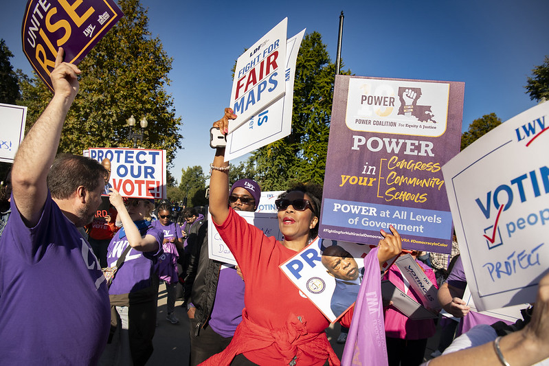 Various people at a fair maps rally holding signs
