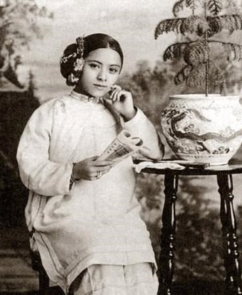 Portrait of Tye Leung Shulze seated at a table with pottery