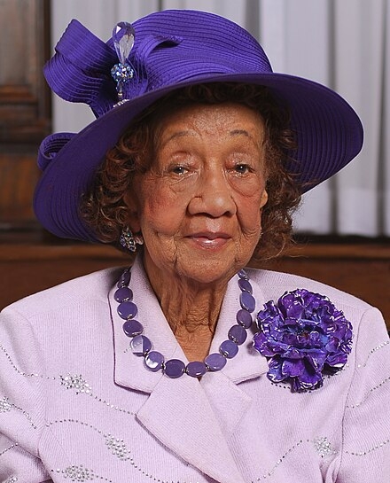 Dorothy Height in a purple outfit smiling to camera