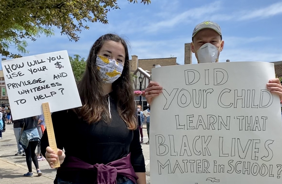 Woman and man holding up protest signs