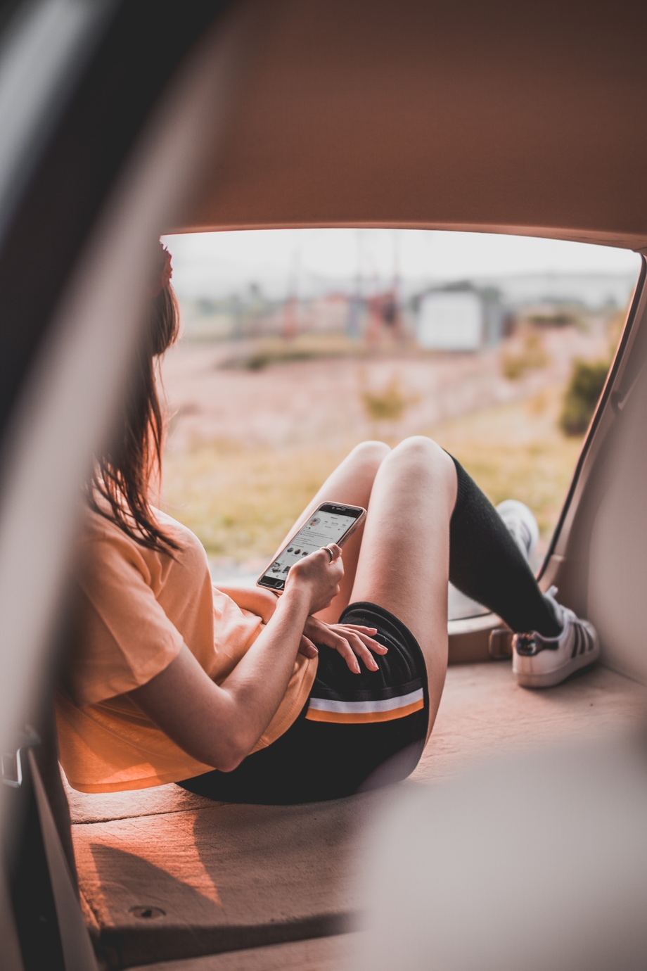 A girl sitting by a window while scrolling on her phone