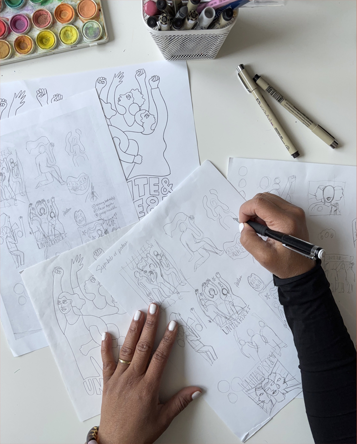 Drafts of the drawing for the Unite and Rise artwork with the hands of the artist drawing over them