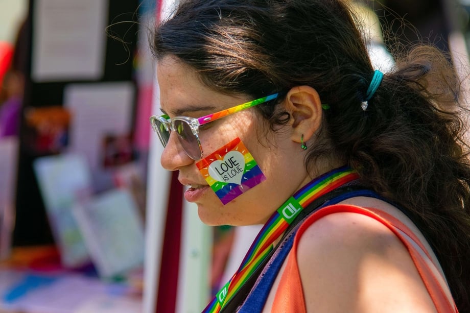 Person with face paint of a rainbow flag and the text 