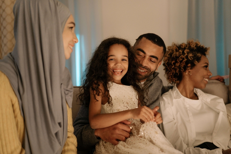 A family sitting inside with a laughing child centered