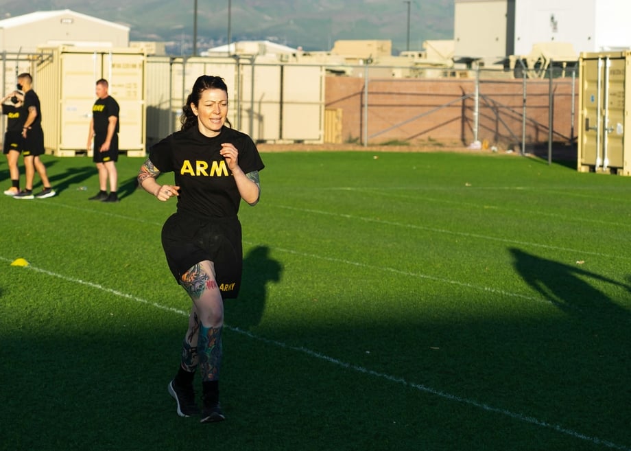 A woman in an army t-shirt running on a field
