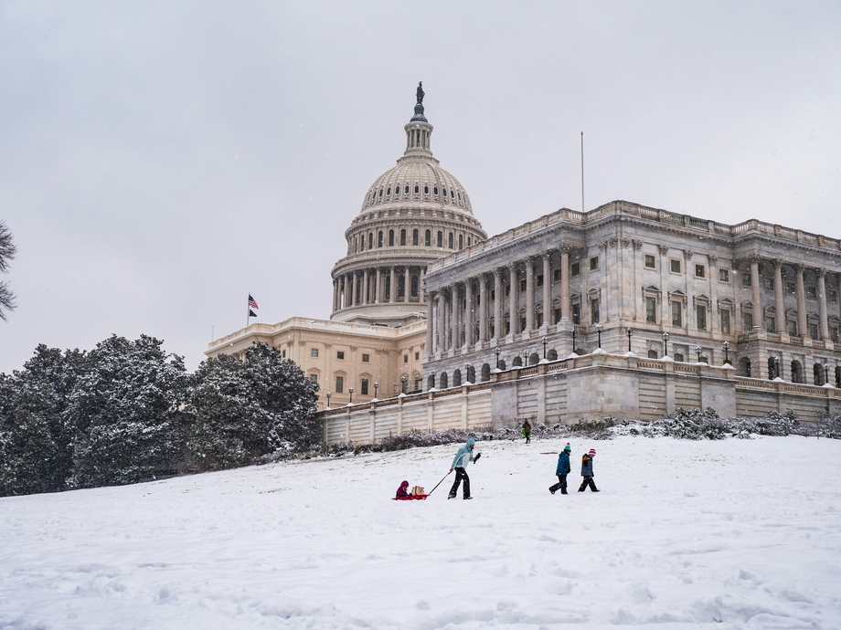 A group pulling a sled on a snowy hill outside the US Capitol Building